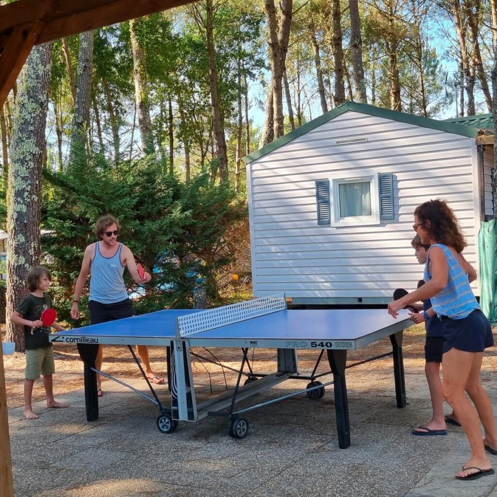 Partie de ping-pong entre campeurs devant un mobil-home