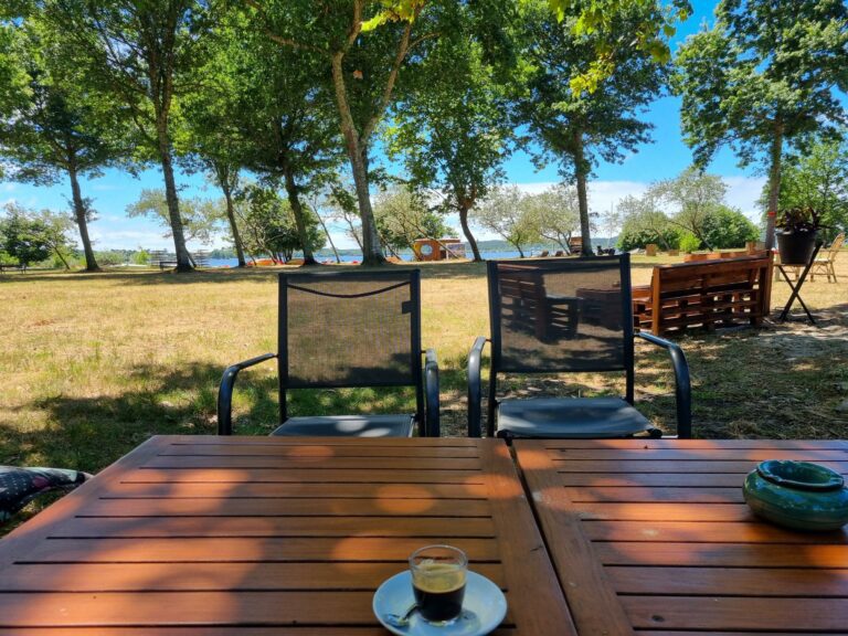 Un café sur une table en bois de la guinguette Why Not, face au lac de Léon