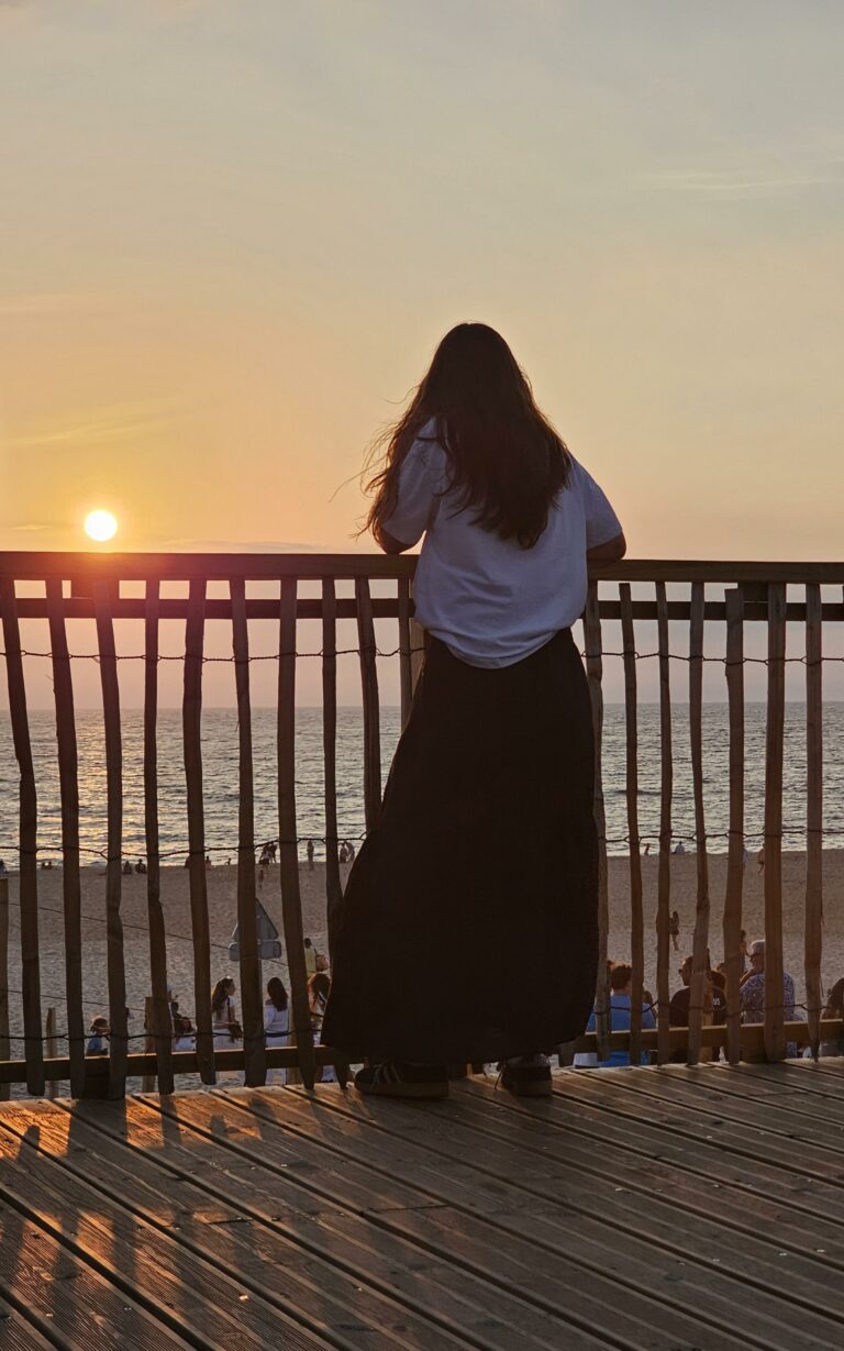 Une jeune fille regarde le coucher de soleil sur l’océan depuis la plage de Vielle-Saint-Girons